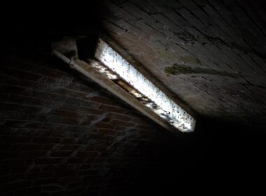 a dark room with a window and a brick wall