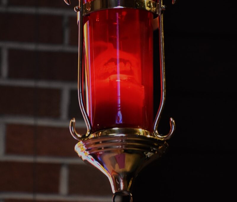 red and gold lamp near brown brick wall