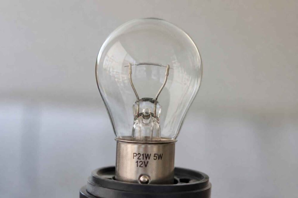Przezroczysta żarówka P21W 5W 12V w metalowej oprawce na czarnym gnieździe